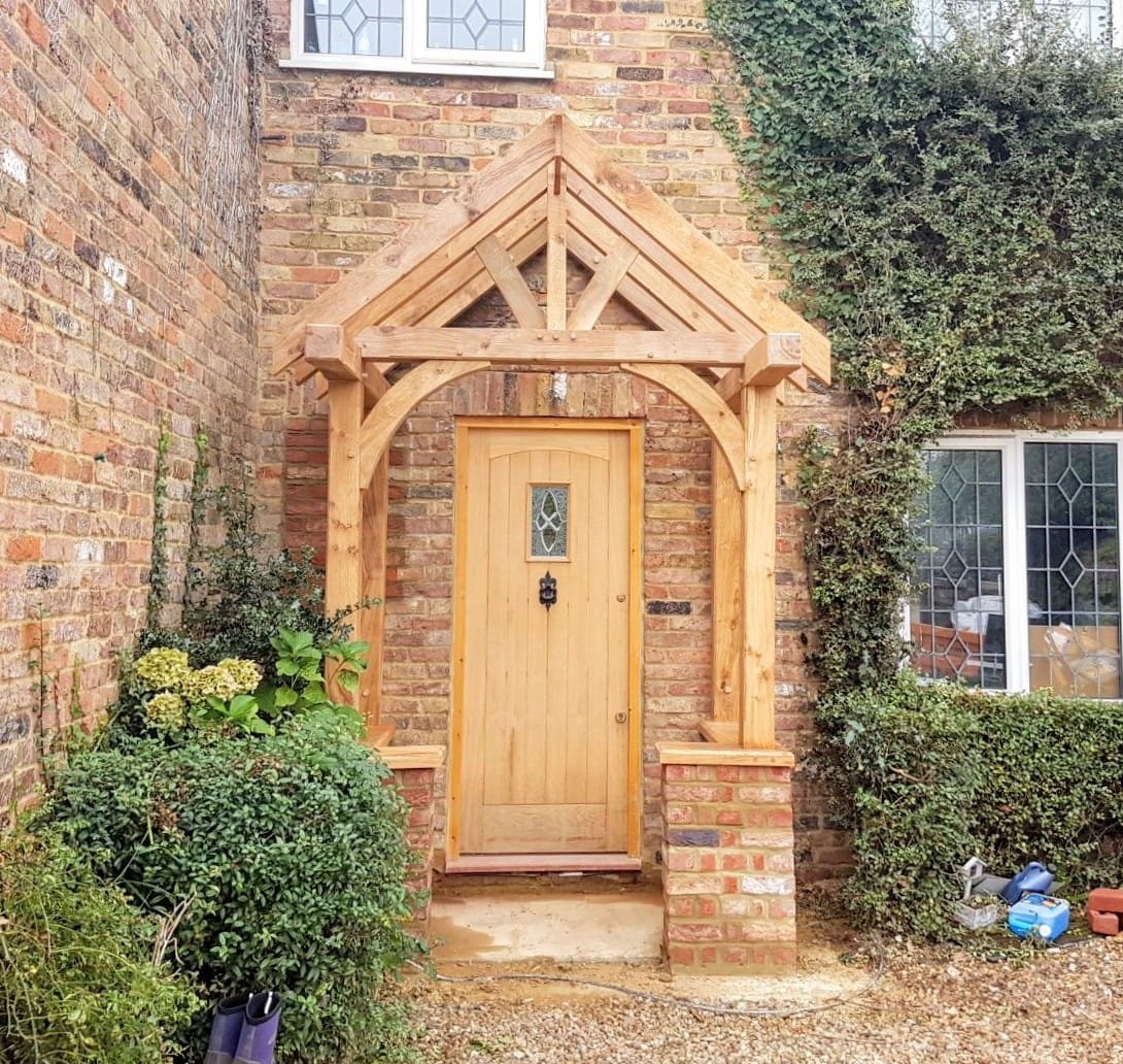 Front view of a solid oak porch situated on 2 brick waste height walls handmade by New Forest Oak